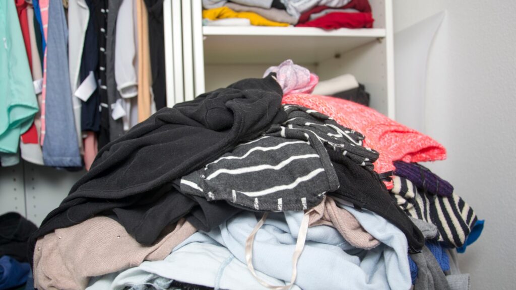 Pile Of Unorganised Clothes In Front Of A Wardrobe