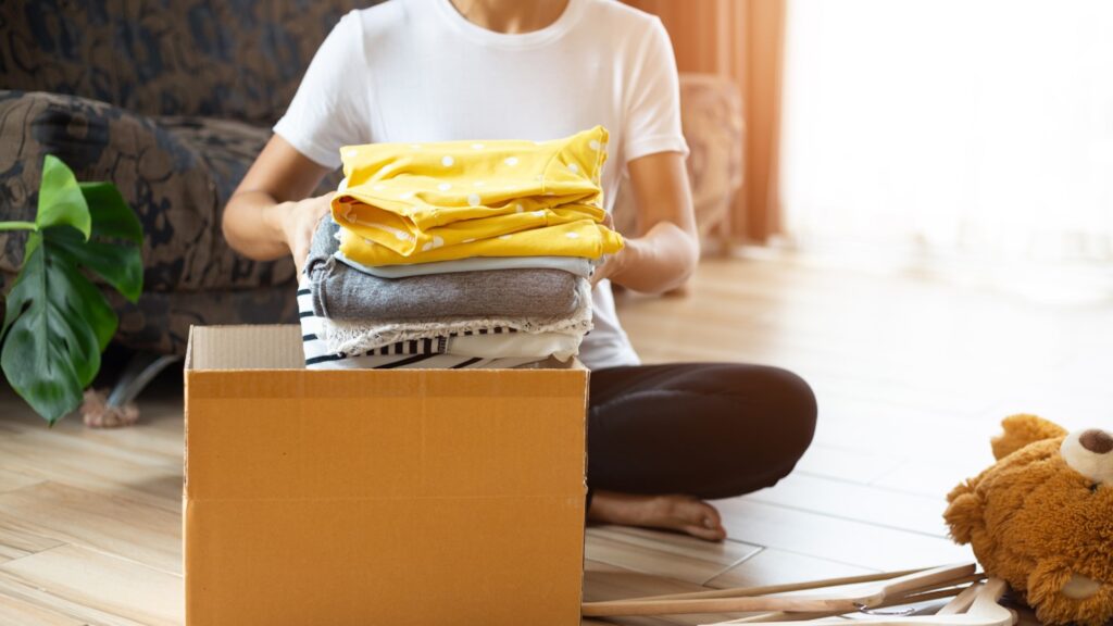 Woman Putting Old Clothes In A Box To Donate